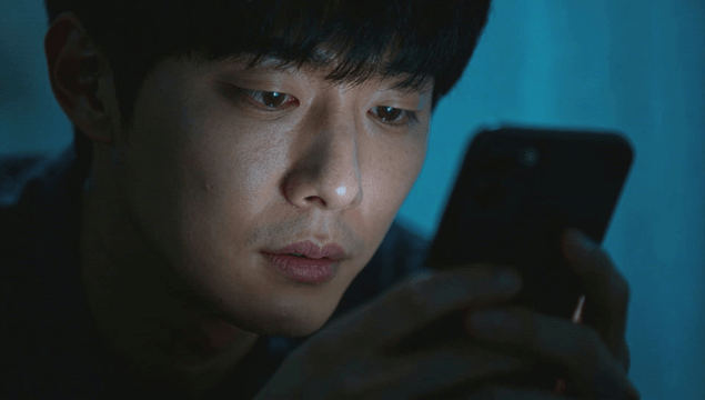 Tired man focusing on a smartphone screen in a dark room