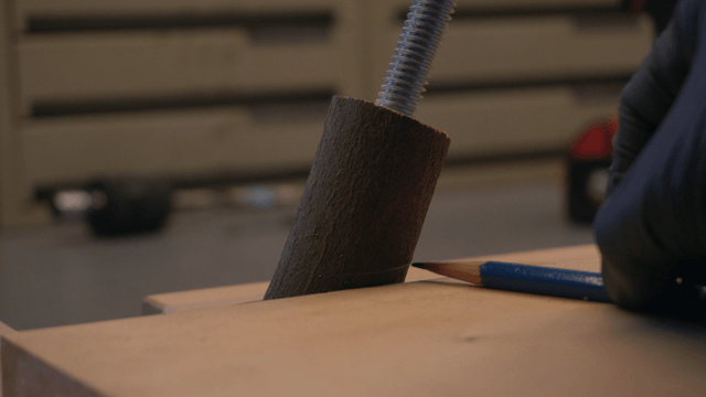 Pencil marking position on wooden block at workbench