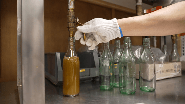 Sesame oil being poured into bottles at a mill