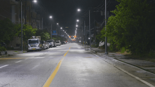 Quiet street with parked cars under streetlights