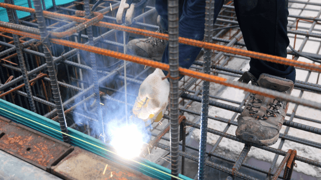 Worker welding steel bars at a construction site