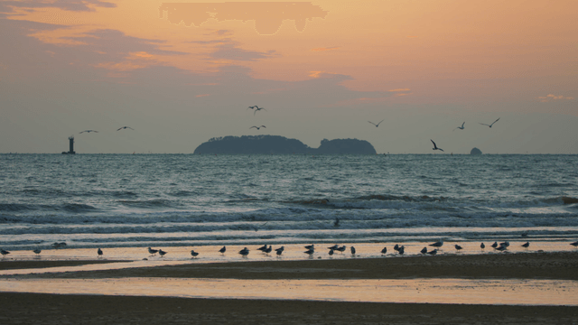 Early evening beach with distant island and lighthouse