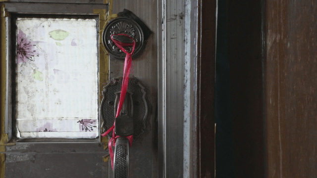 Old door with a red ribbon tied to the handle