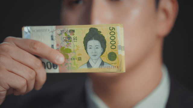 Man smiling with his eyes covered by money