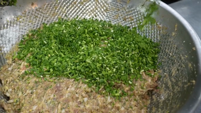 Adding chives to dumpling filling