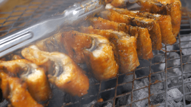 Spicy seasoned eels flipped at once on grill