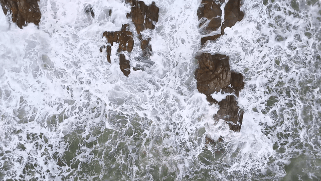 White rough waves crashing into rugged rock gaps