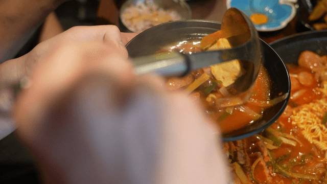 Ladle serving budaejjigae into bowl