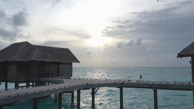 Overwater bungalows at sunset by the sea