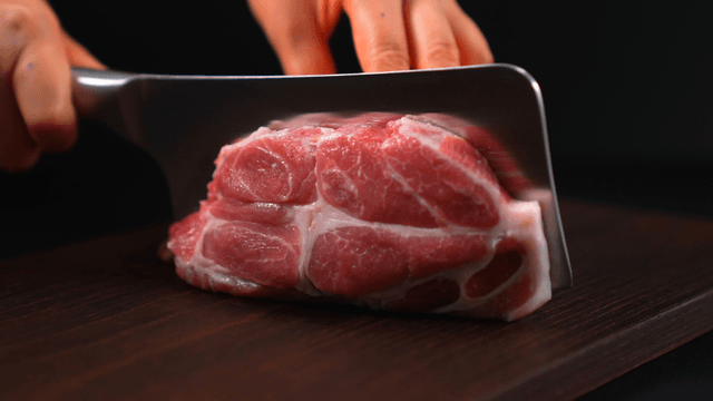 Fresh pork being sliced on a wooden board