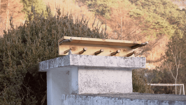 Wooden stand on a stone pillar with mountains in the background