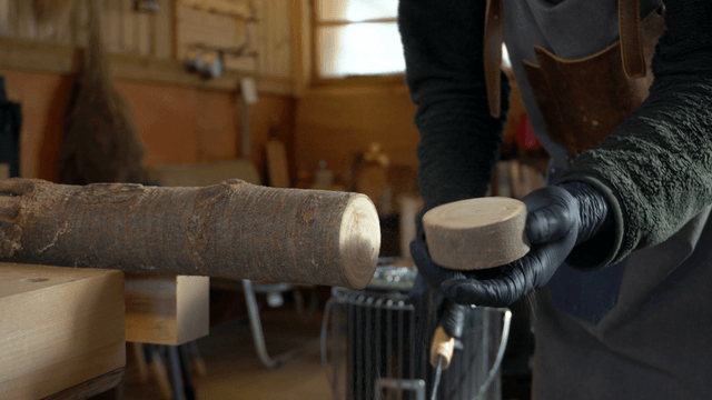 Woodcraft artisan cutting a log in workshop