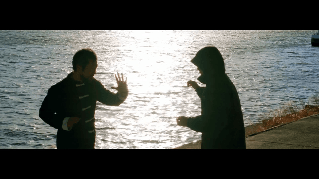 Two people practicing martial arts by the riverside