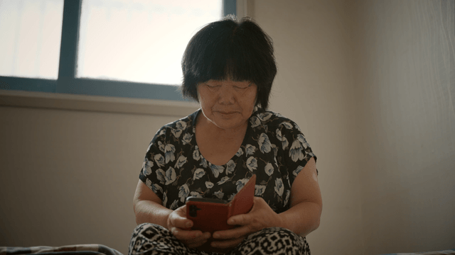 An elderly woman using a smartphone indoors
