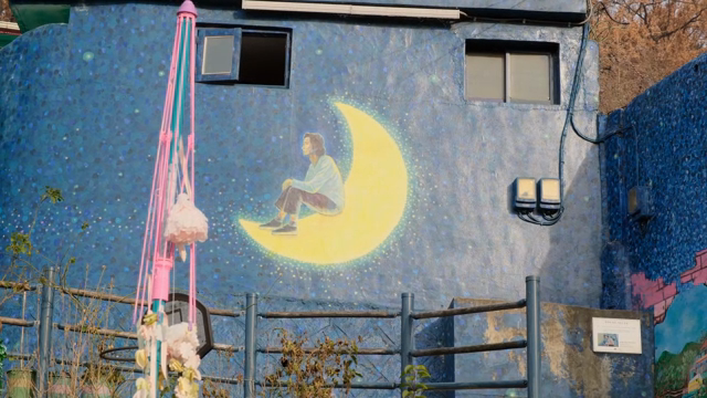 Mural of a person sitting on a crescent moon