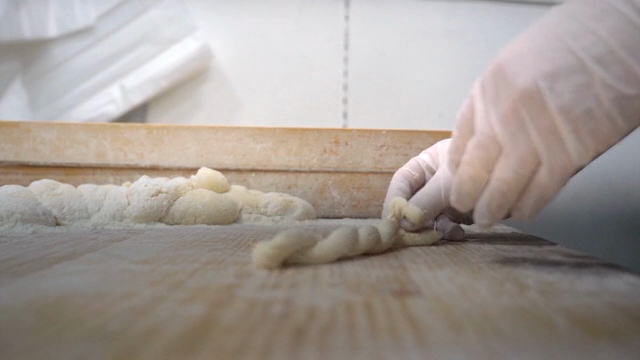 Hands shaping dough on a floured surface