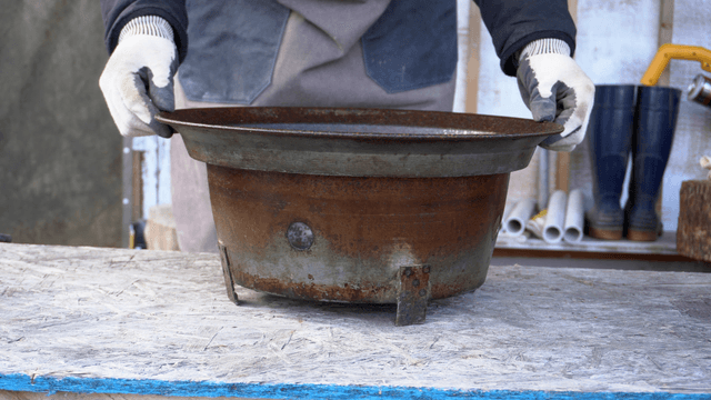 Artisan handling rusty metal containers in workshop