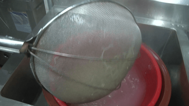 Noodles being strained in a kitchen