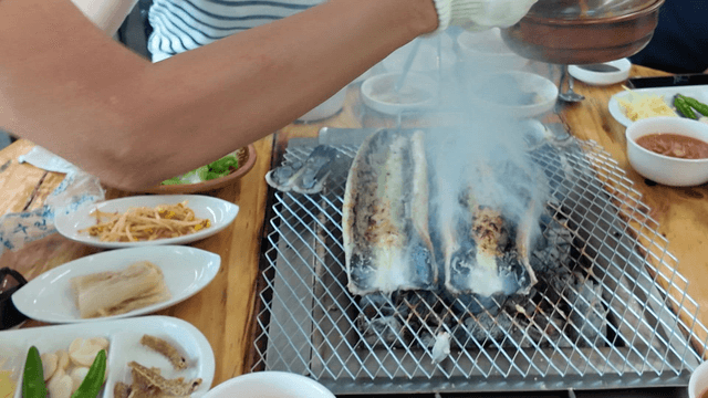 Eels grilling on table with side dishes