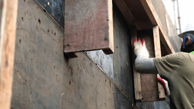 Worker assembling wooden panels at a site