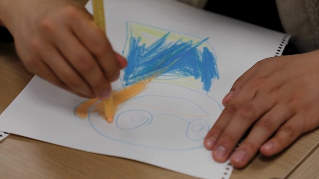 A person drawing with crayons on paper