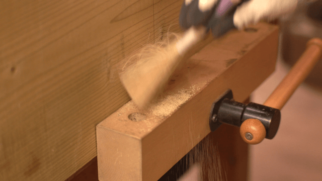 Wooden workbench with sawdust being cleaned