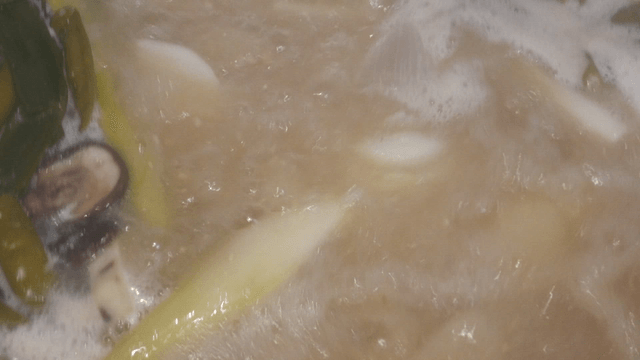 Pot of simmering meat stock with assorted vegetables