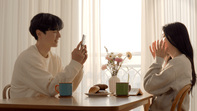 Couple taking photo at breakfast table with bread and coffee