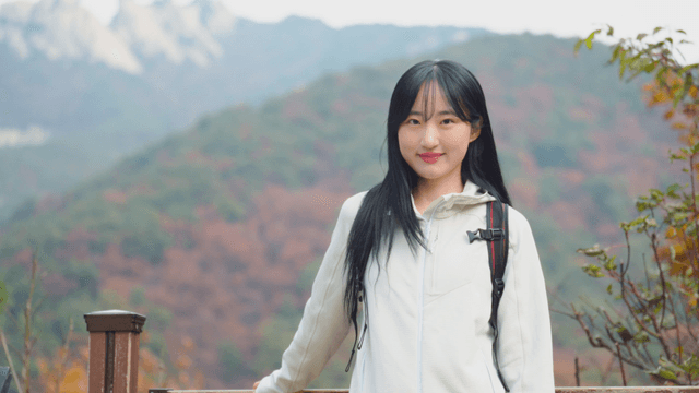 Young woman enjoying summit view in autumn mountain