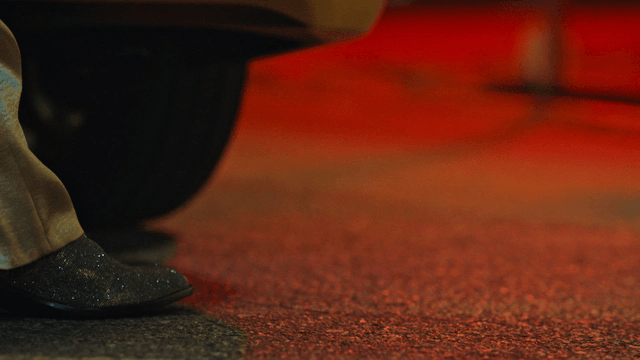 A foot stepping out of a car at night