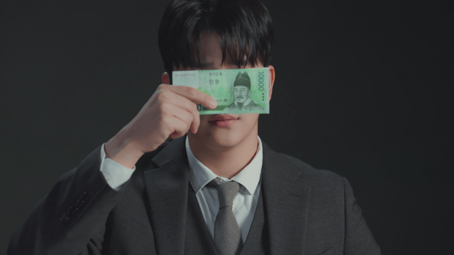 Man showing mixed expressions while covering his face with money