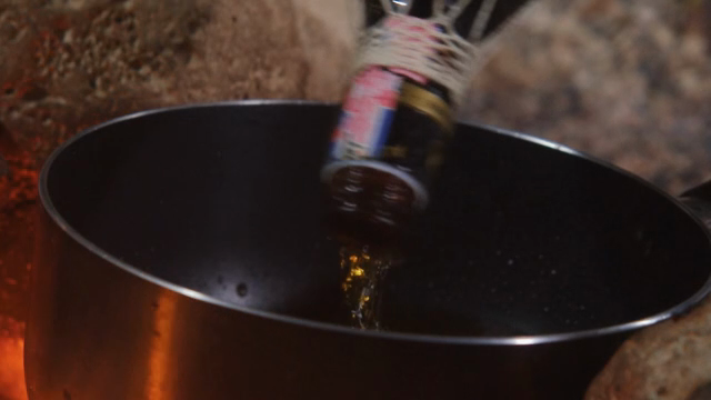 Liquid being poured into a pot over fire