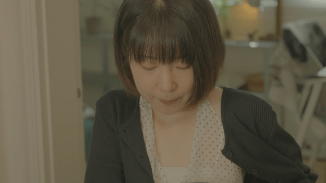 Young woman with bob hair smiling awkwardly while sitting on chair