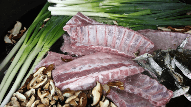 Pork ribs and vegetables soaked in large kitchen pot