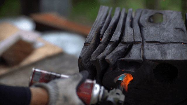 Artisan burning wood at an outdoor workshop