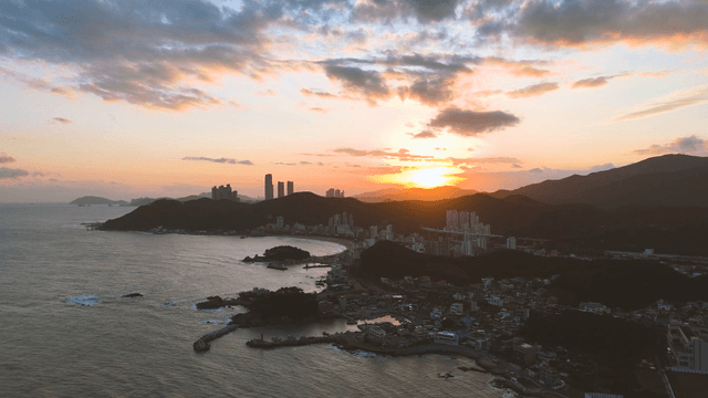 Sunset over a coastal city with mountains
