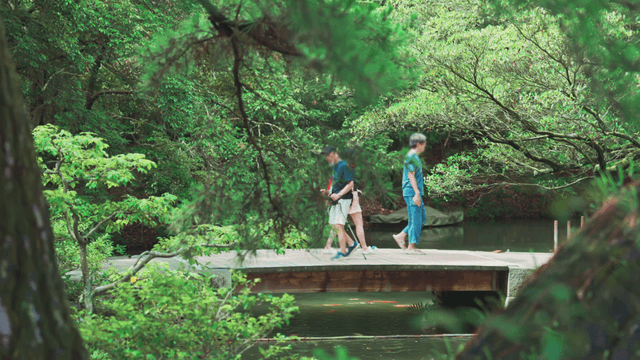 People crossing narrow wooden bridge over lake