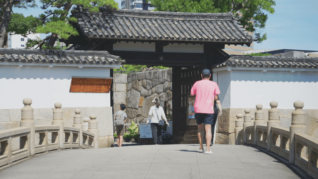 People walking on a bridge towards a traditional gate