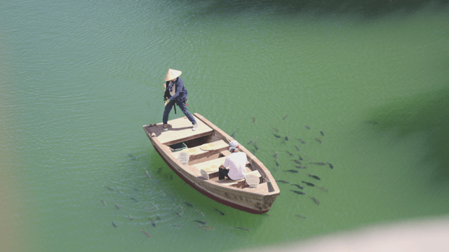 Two people fishing on a boat in a green river