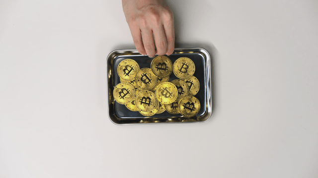 Hand taking a tray with a Bitcoin on it