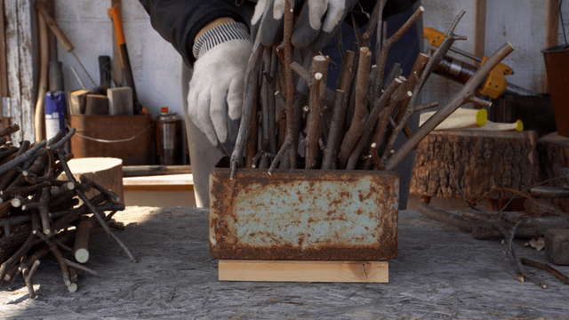 Woodcraft artisan arranging branches in a rusty container