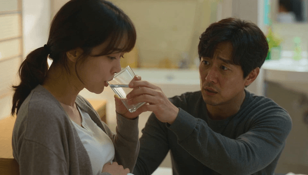 Husband offering water to pregnant wife in bathroom