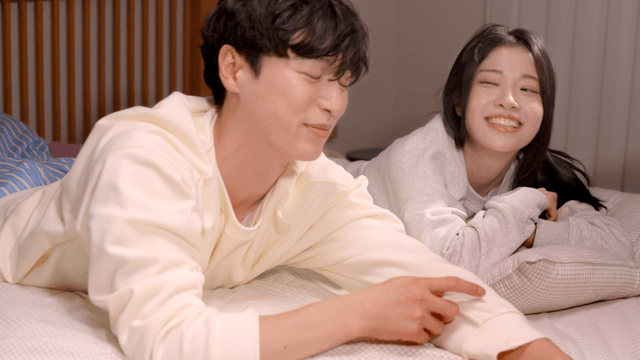 Couple smiling playfully while lying on bed