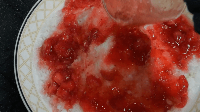 Strawberry syrup poured over shaved ice