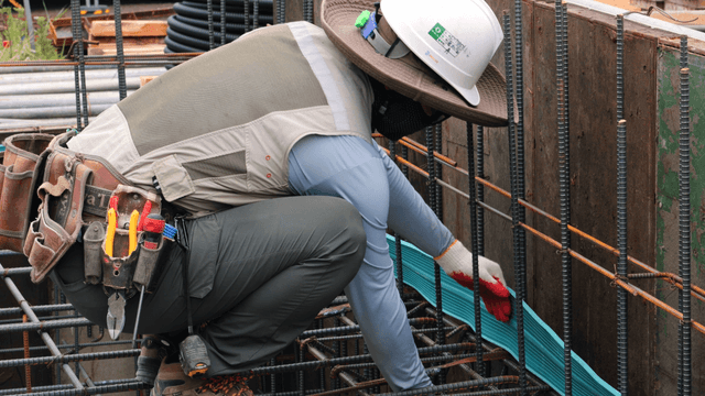 Worker securing pipes at a construction site