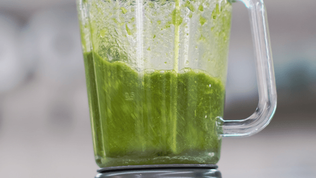 Green smoothie blending in a glass blender