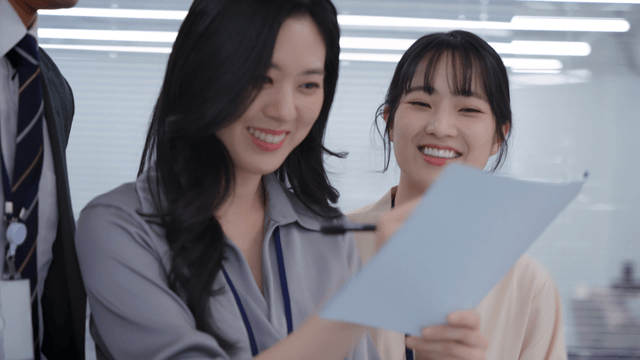 Team members standing and smiling while reviewing meeting documents