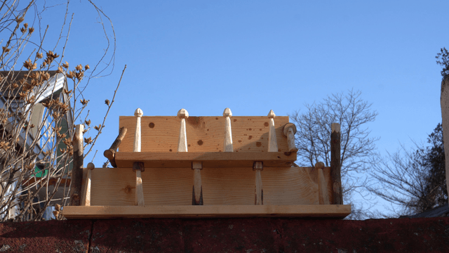 Wooden shelf on bricks in front of bare tree