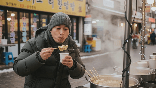Man enjoying warm fish-cake skewers on a cold street