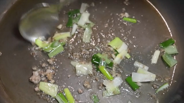 Green onions and meat frying in a pan